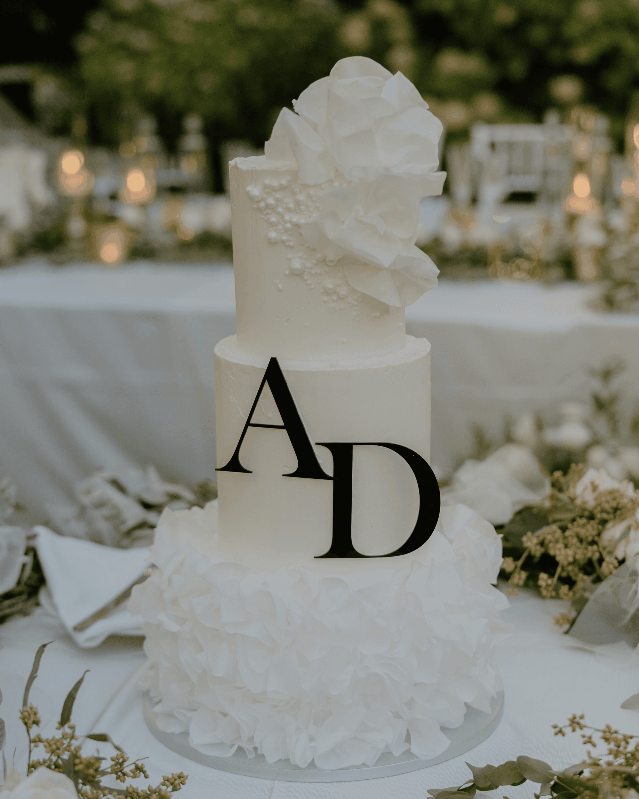 Moderne mehrstöckige Hochzeitstorte mit weißen floralen Details und Initialen